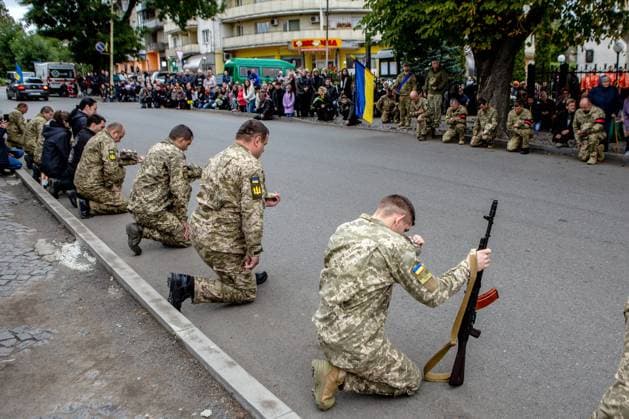 PERECHYN, UKRAINE - SEPTEMBER 25, 2022 - Servicemen kneel to pay their last respects to Senior Lieutenant Armen Petrosian, 50, who died while liberating the northeastern Kharkiv Region from Russian occupation troops as the convoy with the coffin moves through Perechyn, Zakarpattia Region, western Ukraine. Funeral ceremony of Senior Lieutenant Armen Petrosian in Perechyn  Copyright: xSerhiixHudakx