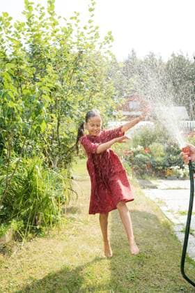 IMAGO Creative: Sommer, Sommertage im Garten Carefree girl dancing in water from hose at garden model released, Symbolfoto property released, LESF00094