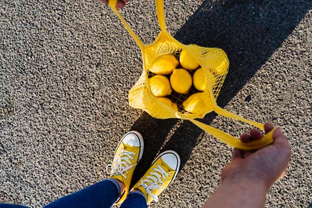 Creative Highlights Symbolbilder Woman standing on road opening mesh bag with lemons model released, Symbolfoto, OSF00812