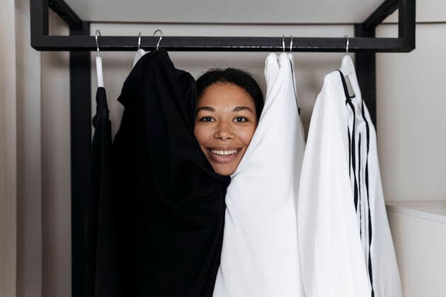 Creative Highlights Symbolbilder Woman sitting inside closet and peeking out from behind clothes model released, Symbolfoto property released, SIF00438