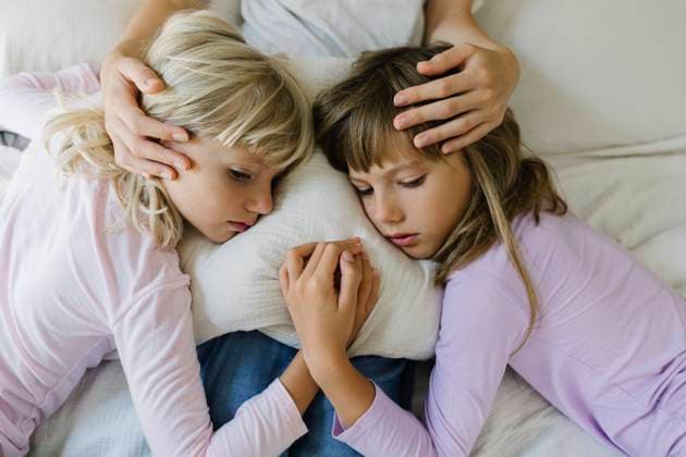 Sad siblings resting over cushion on lap of mother at home model released, Symbolfoto property released, TYF00397