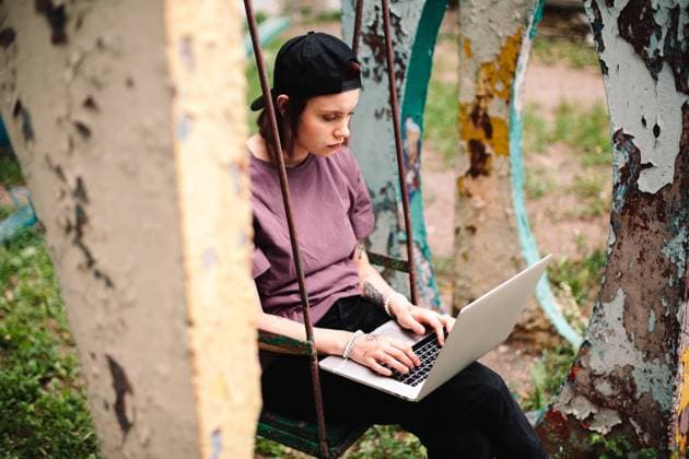 IMAGO Creative: Gesundheit, Magersucht, Bulimie IMAGO Creative, Jahreszeit Herbst, Ferien Young female student using laptop sitting on a swing CR_DMBE220926-1040496-01 ,model released, Symbolfoto