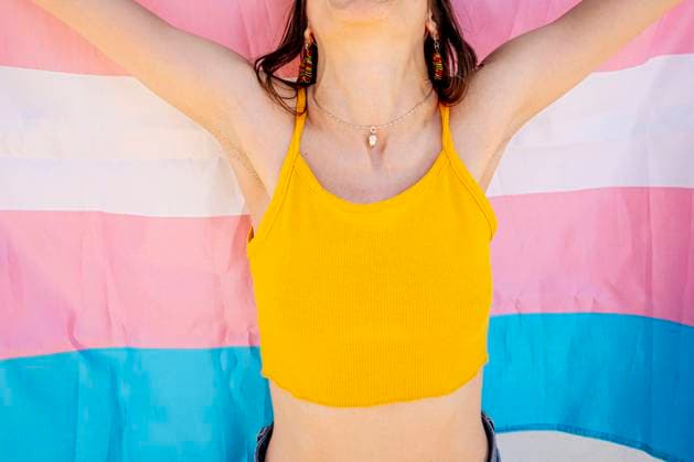 Cropped unrecognizable female in crop top and holding transgender flag behind back on sunny summer day on street anonymous woman JoseLuisCarrascosa_ID768_28583_018 Copyright: xJosexLuisxCarrascosax Model Released