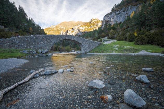Fast river with transparent water flowing under stone bridge against mountain peak and cloudy sky on sunny day in Ordesa y Monte Perdido National Park in Huesca, Spain, Model released JuanLopez_ID697_25432_013 Copyright: xJuanxLopezx MR