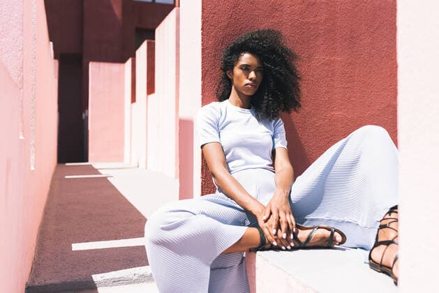 Creative Highlights Symbolbilder Black woman sitting in a colorful geometric building, Model released DavidPrado_MurallaRoja_29 Copyright: xDavidxPradox MR