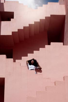 Creative Highlights Symbolbilder Black woman relaxing in a colorful geometric building stairs, Model released DavidPrado_MurallaRoja_38 Copyright: xDavidxPradox MR