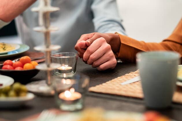 Crop multiracial couple holding hands while sitting together at table with food and candles during dinner, Model released, Property released AntonioOvejero_FriendsPartyFlat_44 Copyright: xAntonioxOvejerox MR