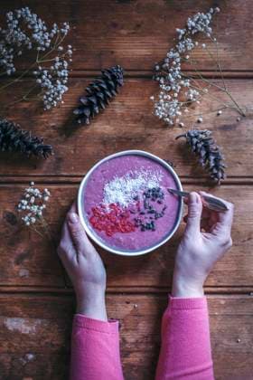 Woman eating raspberry smoothie bowl on a rustic wooden table Woman eating raspberry smoothie bowl on a rustic wooden table Copyright: xLilixBasicxCapaccettixPhotographyx LBC070417-15