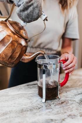 Woman pours hot water from teapot into a French press to make coffee Sioux Falls, South Dakota, United States CR_ASWE210701-770015-01 ,model released, Symbolfoto ,property released
