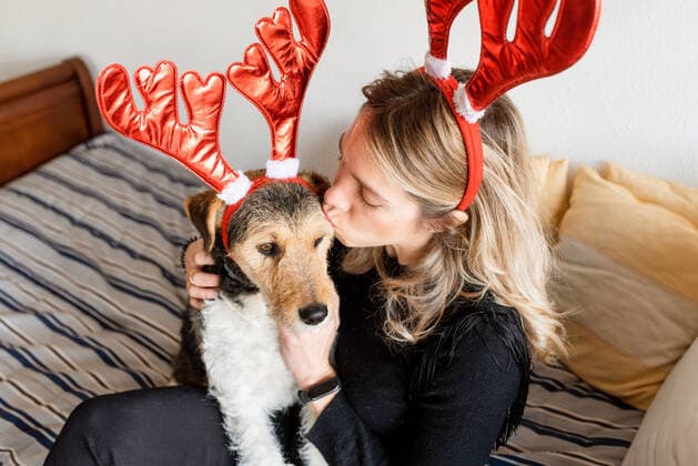 Happy female in decorative deer horns cuddling adorable purebred dog on bed AlbertoMenendez_WomanWithDog_19 Copyright: xALBERTOxMENENDEZxCERVEROx MENIxFx Model Released
