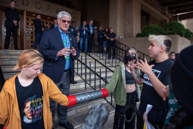 October 3, 2022, USA: Rep. Larry Scott, R-Hobbs, second from left, talks with Jonathan Juarez, from Albuquerque and with YUCCA, and other protesters blocking the entrance to the Eldorado Hotel, in Santa Fe, where the New Mexico Oil and Gas Association is gathering. There are around 50 protesters, organized by YUCCA (Youth United for Climate Crisis Acrtion), protesting against oil and gas exstraction in New Mexico. Also in the photo Annie Eilerman, left, and Valkyrie Gyore, second from right, block the hotel entrance. USA - ZUMAab1_ 20221003_zaf_ab1_010 Copyright: xEddiexMoorex