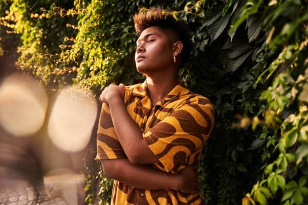IMAGO Creative, Jahreszeit Sommer, Sommer in der Stadt Dreamy young Filipino non binary man wearing cool shirt with earring embracing himself with love standing with eyes closed in green garden ManuelRuiz_ID927_33969_031 Copyright: xManuelxRuizx Model Released