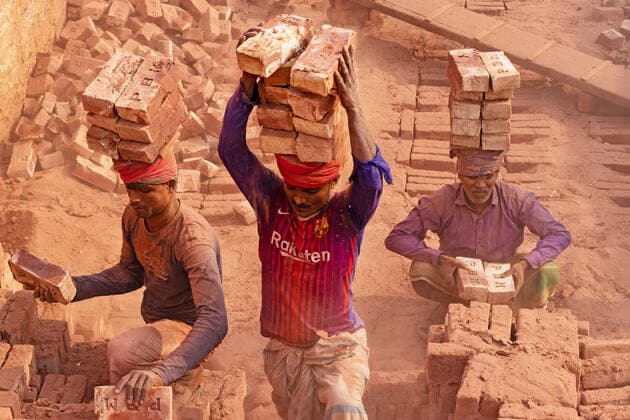 October 13, 2022, Dhaka, Dhaka, Bangladesh: Workers in Dhaka, Bangladesh, carry piles of bricks weighing more than 15 kg on their heads as they are laid out ahead of being baked in a kiln. The labourers Ã¢â‚¬ who are paid less than Ã‚Â£1 a shift Ã¢â‚¬ move up to 1,500 bricks a day in sweltering conditions. Around 4,00,000 low-income migrants arrive in Dhaka from different parts of the country every year to work at brickfields. Long working hours under the scorching sun in the brick fields, massive accumulation of dust, the risk of falling from the trucks and piles of bricks, and carrying excessive loads pose serious health hazards for the workers. Brick kilns emit toxic fumes containing large amounts of carbon monoxide, nitrogen oxide - ZUMAs231 20221013_zip_s231_014 Copyright: xJoyxSahax