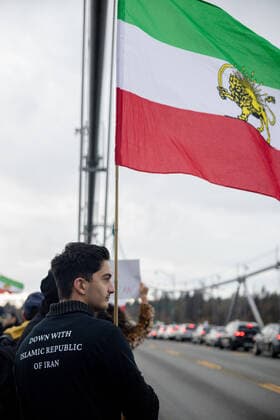 October 29, 2022, Vancouver, British Columbia, Canada: A man wearing a jacket that reads Ã¢â‚¬oeDown with Islamic Republic of IranÃ¢â‚¬Â holds an Iranian flag during a protest in Vancouver, British Columbia...The protest brought people together on the Lions Gate Bridge to form a human chain Vancouver Canada - ZUMAw171 20221029_znp_w171_010 Copyright: xRyanxWalterxWagnerx