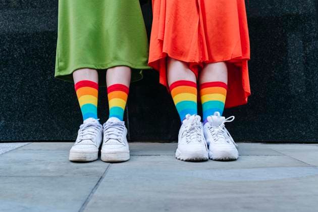 Multiracial lesbian couple wearing colorful socks in front of wall model released, Symbolfoto, ASGF02973