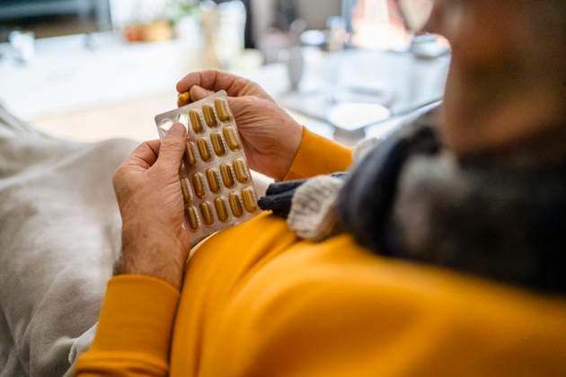 Man removing capsule from blister pack at home model released, Symbolfoto property released, DIGF19029