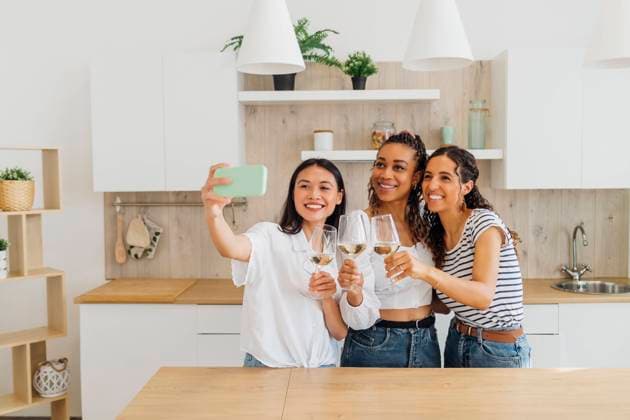 IMAGO Creative, Lifestyle, Leben in einer Wohngemeinschaft, WG Happy friends talking selfie with wineglasses in kitchen model released, Symbolfoto property released, MEUF08058