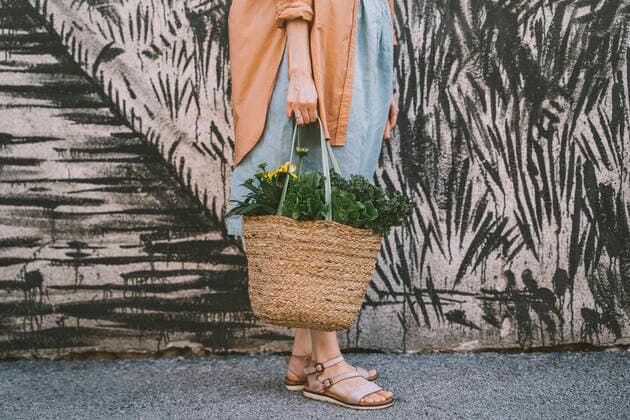 Woman with leafy vegetables and flowers in wicker bag by patterned wall model released, Symbolfoto, NDEF00015