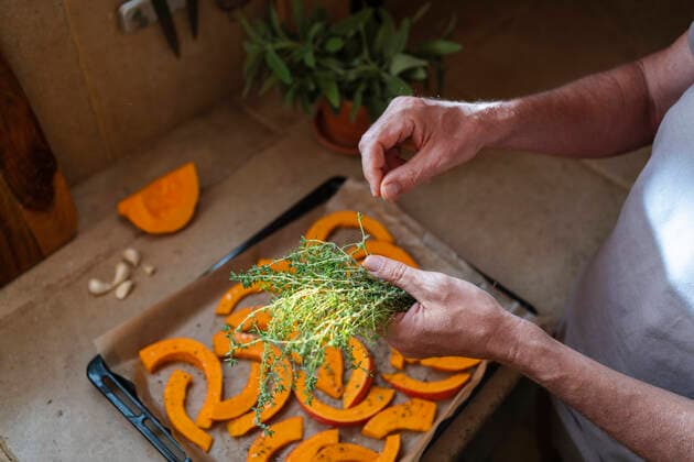 Hands of man picking thyme over slice of pumpkin in tray model released, Symbolfoto property released, SVKF00580