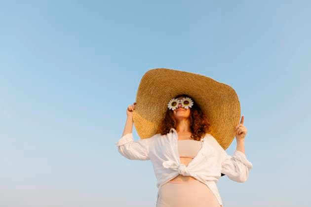 Smiling woman wearing sunflower sunglasses and oversized straw hat on sunny day model released, Symbolfoto, TYF00431