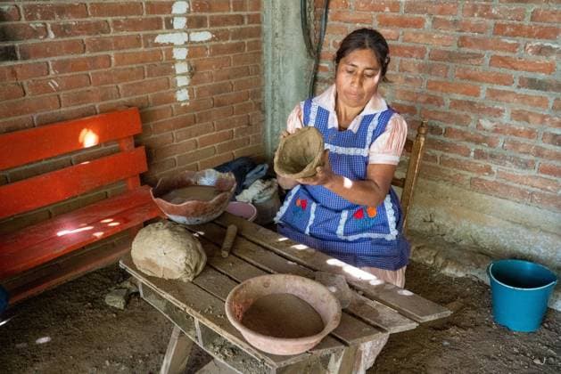 IMAGO Cultures of the world, Zapotec Kultur in Mexiko Making red clay pottery. The potter begins to shape red clay by hand to make a pot in San Marcos Tlapazola, Mexico. She is wearing a traditional satin dress and apron typical of her village. San Marcos Tlapazola Oaxaca Mexico Copyright: xJonxG.xFullerx 3653-JGF-handicrafts-red clay pottery-MX