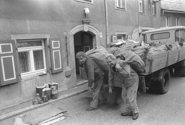 DDR, Sachsen, historisch, Wirtschaft, Volkswirtschaft, Betriebe (VEB Volkseigene Betriebe): Dresdner Kohlehandel, Betriebsteil Pirna, Arbeitsalltag, Anlieferung beim Kunden Privathaushalt, Abladen von Kohlesäcken vom W50, Arbeiter namentlich nicht benannt. August 1987. Veröffentlichung in Sächsische Zeitung am 21.08.1987: Der nächste Winter kommt sicher. Einer der fünf Betriebsteile des Dresdner Kohlehandels ist der in Pirna. Hier kommt an jedem Tag ein Güterzug des Braunkohlenkombinats Schwarze Pumpe an, aus dem bis zu 600 Tonnen Briketts und 200 Tonnen Klarkohle entladen werden müssen. Insgesamt sind es 1.100 Tonnen, die von den über 100 Kohlearbeitern mit Groß- und Kleinfahrzeugen, vom Skoda, W 5O, Robur bis zum Multicar verte Copyright: xSZ GunterxHübnerx 0000010121133596 ! ACHTUNG Aufnahmedatum laut Beschriftung