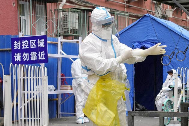Zero COVID policy in China An official in protective gear stands in front of a building in Beijing where public access is prohibited due to COVID-19 cases on Nov. 22, 2022.  A14AA0001360570P