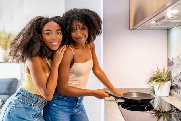 Young friends with cooking pan on glass stove in kitchen model released, Symbolfoto property released, DLTSF03272