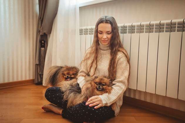 Smiling woman with dogs leaning on radiator at home model released, Symbolfoto property released, MDOF00123
