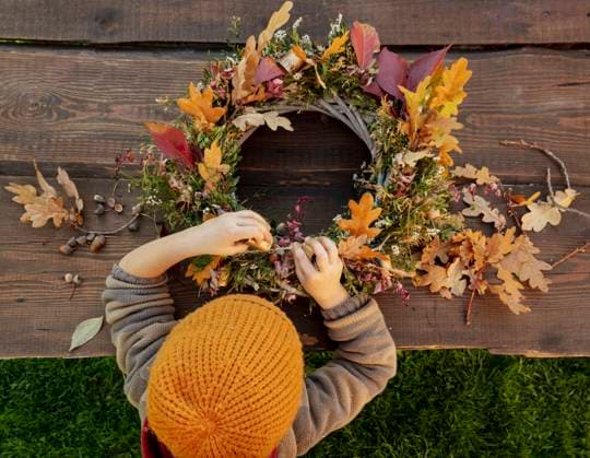 IMAGO Creative: Herbst, Herbstkränze Boy wearing knit hat making autumn wreath on wooden table model released, Symbolfoto, VSNF00064