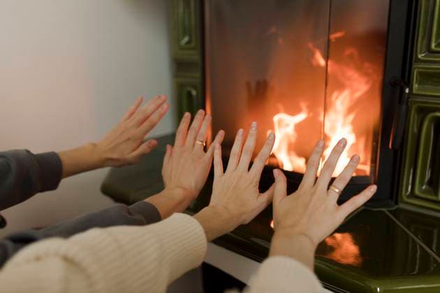 Man and woman warming hands in front of fireplace at home model released, Symbolfoto property released, VIVF00128