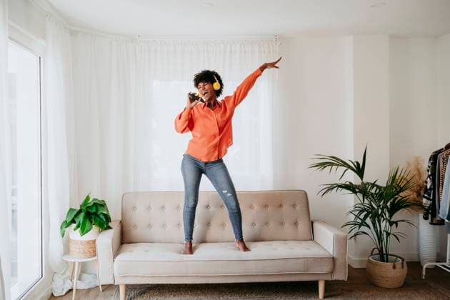 Carefree freelancer dancing and singing on sofa at home office model released, Symbolfoto property released, EBBF06910