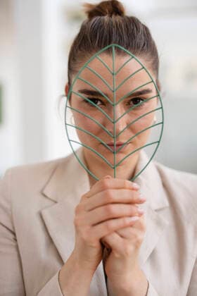Creative Highlights Symbolbilder Businesswoman looking through leaf shape model in office model released, Symbolfoto property released, JOSEF14708