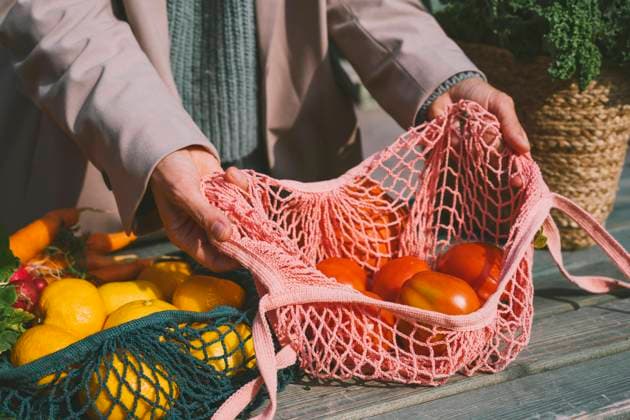 Hands of woman showing tomatoes in mesh bag on table model released, Symbolfoto, NDEF00038