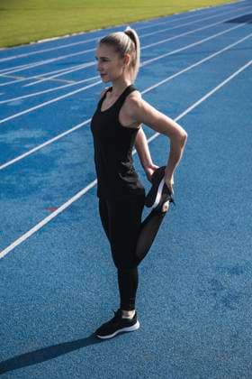 IMAGO Creative, Neujahr, Vorsätze, Sport Young sportswoman stretching leg on track model released, Symbolfoto, UUF27790