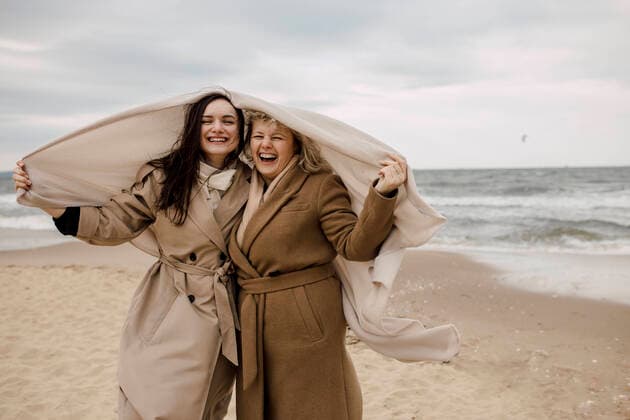 Creative Highlights Symbolbilder Happy mother and daughter with blanket standing at beach model released, Symbolfoto, VIVF00181