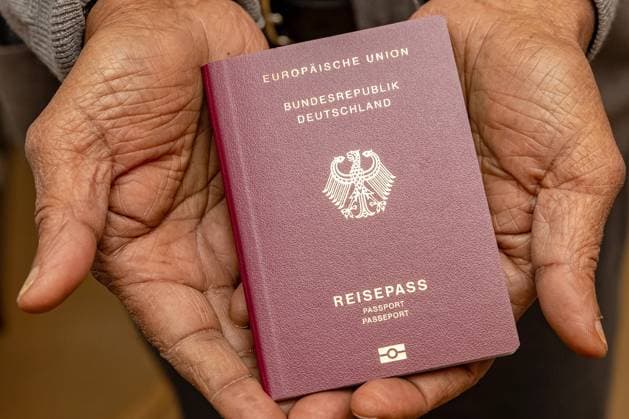 Deutscher Reisepass - Symbolbild Einbürgerung DEU, Deutschland, Hamburg: Ein Mann mit Migrationshintergrund hält seinen deutschen Reisepass in den Händen. Symbolbild für Einbürgerung. Hamburg Hamburg Deutschland *** German passport symbol image naturalization DEU, Germany, Hamburg A man with migration background holds his German passport in his hands symbol image for naturalization Hamburg Hamburg Germany