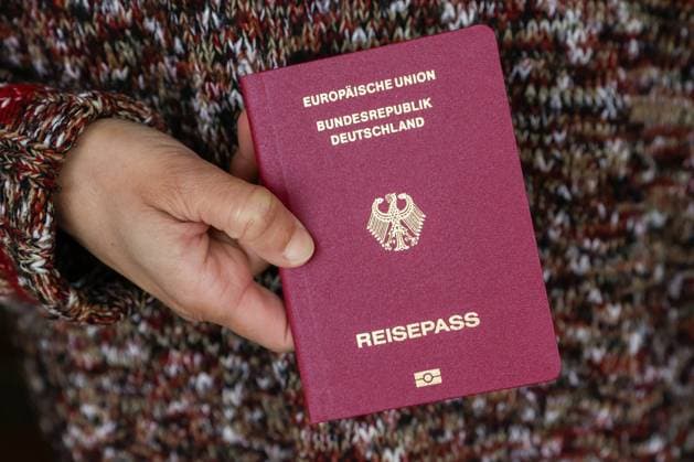 Deutscher Reisepass - Symbolbild Einbürgerung DEU, Deutschland, Hamburg: Ein Frau mit Migrationswurzeln hält ihren deutschen Reisepass in den Händen. Symbolbild für Einbürgerung. Hamburg Hamburg Deutschland *** German passport symbol image naturalization DEU, Germany, Hamburg A woman with migration roots holds her German passport in her hands symbol image for naturalization Hamburg Hamburg Germany