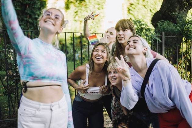 Happy woman taking selfie with friends gesturing and showing peace sign