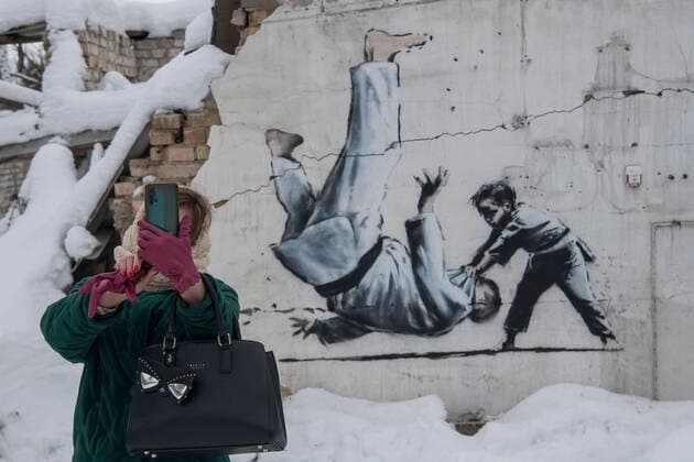 Bilder des Jahres 2022, News 12 Dezember Graffiti Made By Banksy In The Borodianka And Hostomel Towns Near Kyiv A woman is taking a selfie with a graffiti made by Banksy on the wall of a destroyed residential building among debris covered by snow in Borodianka, Ukraine, on December 6, 2022 Borodianka Ukraine  Copyright: xMaxymxMarusenkox originalFilename: musienko-notitle221206_np5ce.jpg