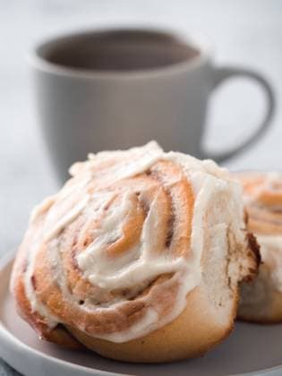 Vegan cinnamon rolls with topping, top view Vegan swedish cinnamon buns Kanelbullar with pumpkin spice,topping vegan cream cheese in plate with tea cup on table. Idea and recipe pastries - perfect cinnamon rolls.Copy space.Shallow DOF. Vertical Copyright: xZoonar.com OlgaxSergeevax 15963702