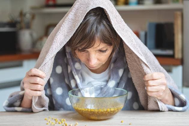 Kamillendampfbad - Hausmittel bei Erkältung und Husten - Frau inhaliert über einer Glasschüssel mit Kamillenblüten , model released - Deutschland *** Chamomile steam bath home remedy for cold and cough woman inhales over glass bowl with chamomile flowers , model released Germany xRMx