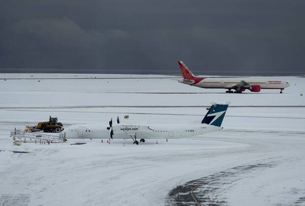 December 20, 2022, RICHMOND, BC, CANADA: A worker clears snow from the apron as Westjet and Air India aircraft sit idle at Vancouver International Airport after a snowstorm crippled operations leading to cancellations and major delays, in Richmond, B.C., on Tuesday, December 20, 2022. RICHMOND CANADA  - ZUMAc35_ 20221220_zaf_c35_048 Copyright: xDarrylxDyckx
