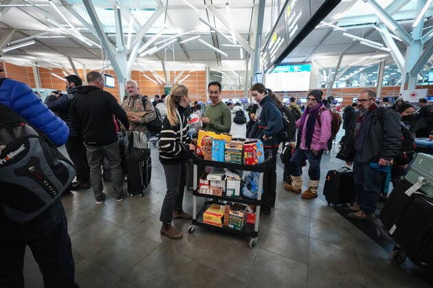 December 20, 2022, RICHMOND, BC, CANADA: An airport employee distributes snacks and water to passengers at Vancouver International Airport after a snowstorm crippled operations leading to cancellations and major delays, in Richmond, B.C., on Tuesday, December 20, 2022. RICHMOND CANADA  - ZUMAc35_ 20221220_zaf_c35_064 Copyright: xDarrylxDyckx