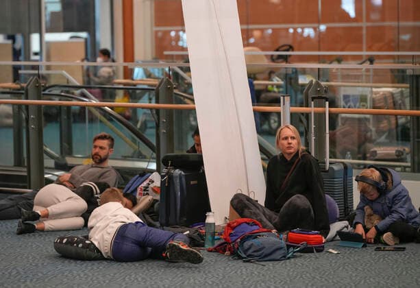 (221220) -- RICHMOND (CANADA), Dec. 20, 2022 -- People wait on the floor at Vancouver International Airport in Richmond, British Columbia, Canada, on Dec. 20, 2022. Thousands of travelers were stuck at the Vancouver International Airport on Tuesday as many flights were cancelled or delayed due to the snowstorm. (Photo by Xinhua) CANADA-VANCOUVER INTERNATIONAL AIRPORT-SNOWSTORM-STRANDED PASSENGERS LiangxSen 
