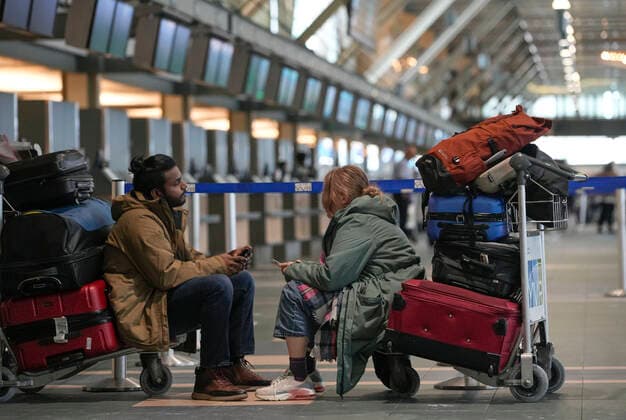 (221220) -- RICHMOND (CANADA), Dec. 20, 2022 -- People sit on trolleys at Vancouver International Airport in Richmond, British Columbia, Canada, on Dec. 20, 2022. Thousands of travelers were stuck at the Vancouver International Airport on Tuesday as many flights were cancelled or delayed due to the snowstorm. (Photo by Xinhua) CANADA-VANCOUVER INTERNATIONAL AIRPORT-SNOWSTORM-STRANDED PASSENGERS LiangxSen 