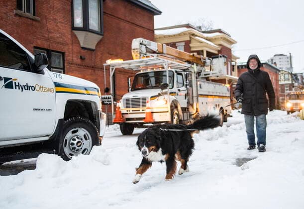 December 23, 2022, Ottawa, ON, CAN: A man walks his dog past Hydro Ottawa utility vehicles responding to power outages in parts of Ottawa s Golden Triangle neighbourhood, as a winter storm warning is in effect, on Friday, Dec. 23, 2022. Ottawa CAN  - ZUMAc35_ 20221223_zaf_c35_008 Copyright: xJustinxTangx