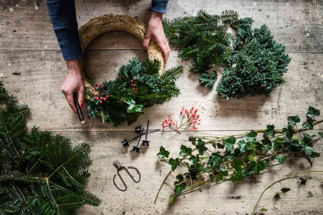 Hands of woman preparing Christmas wreath made of spruce, juniper, ivy, and rose hips model released, Symbolfoto, EVGF04190