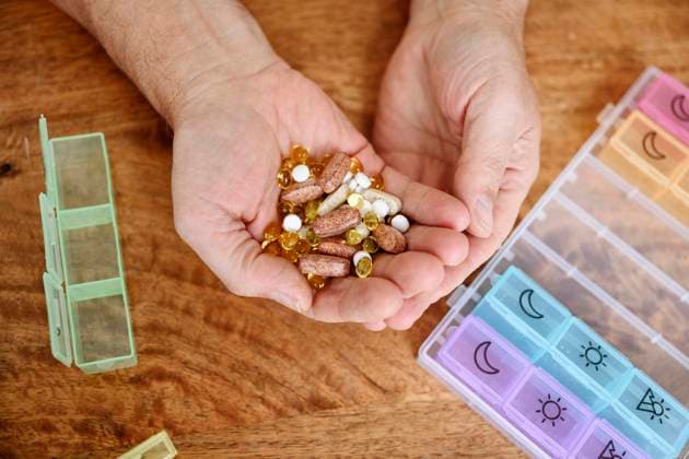 Man holding different pills in hand on table model released, Symbolfoto property released, EYAF02375