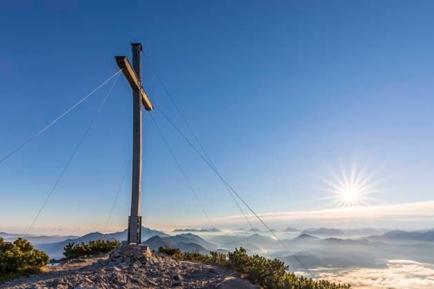 Germany, Bavaria, Summit cross of Herzogstand mountain with sun rising in background, FOF13189